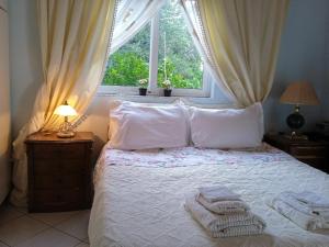 a bedroom with a bed with white sheets and a window at Rosemary House in Sarandë
