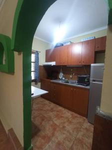 a kitchen with wooden cabinets and a green archway at ΓΑΛΗΝΗ 2 in Skála Stólou
