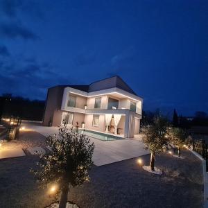 a large building with a swimming pool at night at Villa La Vie in Garica