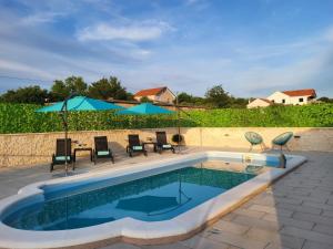 a swimming pool with chairs and umbrellas on a patio at Villa MyDream in Lađevci