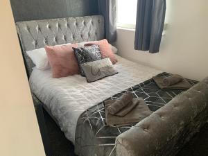 uma cama com almofadas com cabeceira cinzenta em SUNNY PRESTATYN APARTMENT em Prestatyn