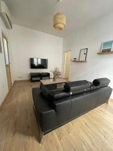 a living room with a black leather couch and a flat screen tv at Cosy nid douillet au cœur du centre ville de Perpignan in Perpignan