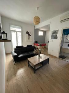 a living room with a black couch and a coffee table at Cosy nid douillet au cœur du centre ville de Perpignan in Perpignan