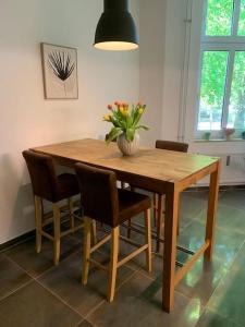 a wooden table with chairs and a vase of flowers on it at Ferienwohnung Parkblick - Balkon 77m2 in Bad Rothenfelde