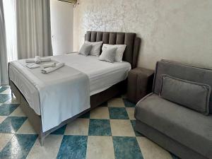 a bedroom with a large bed and a chair at Apartments & Rooms Elite in Dobra Voda