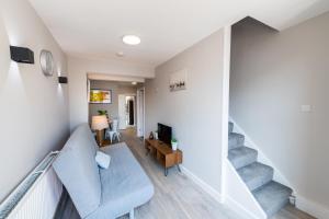 a living room with a blue couch and stairs at City Centre 4 Bed Holiday Home in Maidstone in Kent