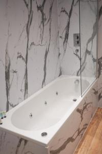 a white tub in a bathroom with a marble wall at S.H Apartments in Glasgow