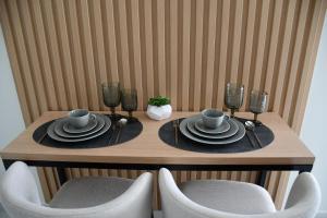 einem Holztisch mit Tellern, Tassen und Stühlen in der Unterkunft URBAN SUITES ATHENS in Athen