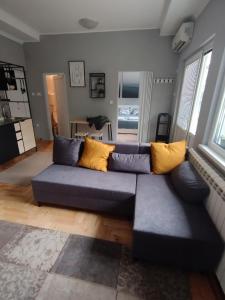 a living room with a blue couch with yellow pillows at Apartman Aleksandra in Smederevo