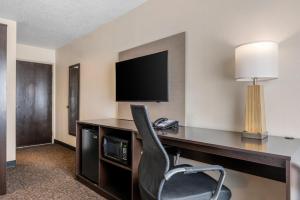a hotel room with a desk with a television and a chair at Sleep Inn in Naperville