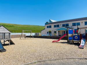 a playground with two swings and a slide at 170 Newquay Bay Resort in Porth