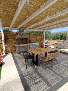eine Terrasse mit einem Tisch, Stühlen und einem Grill in der Unterkunft VILLA GEM POUNTA in Pounda
