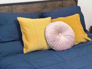 a pink pillow on a blue couch with yellow pillows at Spacious Studio - minutes from MIA airport in Miami