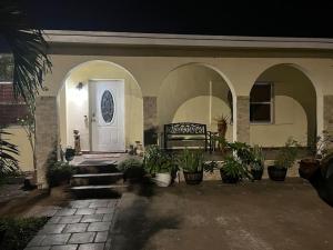 een huis met een veranda met een bank en potplanten bij Spacious Studio - minutes from MIA airport in Miami