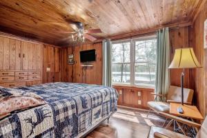a bedroom with wooden walls and a bed and a tv at Hide-A-Way Waterfront Cottages in Lake Luzerne