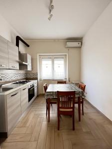 een keuken met een tafel en stoelen en een keuken met witte kasten bij Piano terra centro mare in Ladispoli