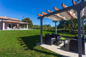 een pergola met stoelen en een tafel in de tuin bij Modern House with private pool in Žminj