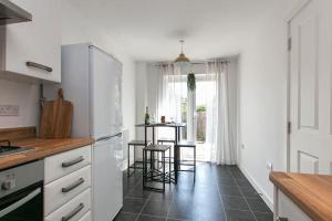 a kitchen with white cabinets and a table with stools at Central Stylish House in Colchester in Colchester