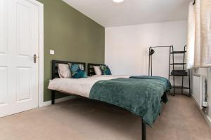 a bedroom with a bed with a green blanket at Central Stylish House in Colchester in Colchester