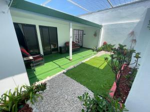 um pequeno jardim numa casa com relvado verde em 3 Min from SJO airport Kaeli em Alajuela
