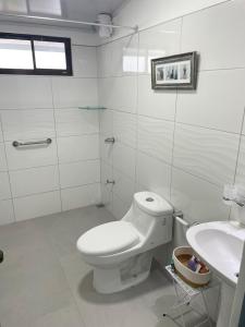 a white bathroom with a toilet and a sink at 3 Min from SJO airport Kaeli in Alajuela City