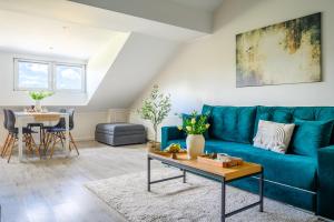 uma sala de estar com um sofá azul e uma mesa em Apartamenty Mieszka I em Łódź