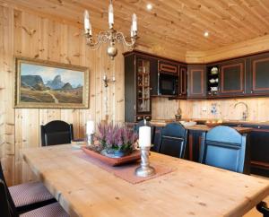 a dining room with a wooden table and a kitchen at Leilighet sentralt på Beitostølen in Beitostøl