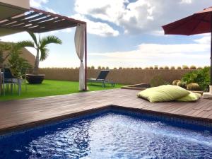 聖克魯斯－德特內里費的住宿－Precioso chalet en Santa Cruz con piscina，后院设有游泳池和带遮阳伞的甲板