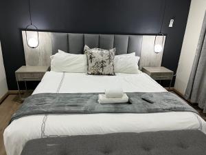 1 dormitorio con 1 cama blanca grande y 2 mesas en Empire Bed & Breakfast, en Leribe