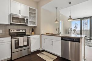 una cocina con armarios blancos y electrodomésticos de acero inoxidable en Piedmont Park 2 bdrm en Atlanta