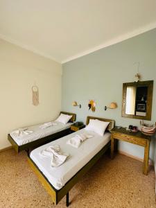 two beds in a room with a table and a mirror at Ancora Hotel in Poros