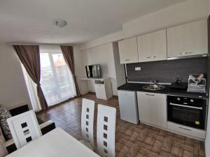 a kitchen with white cabinets and a table and chairs at Arapya Apartments in Tsarevo