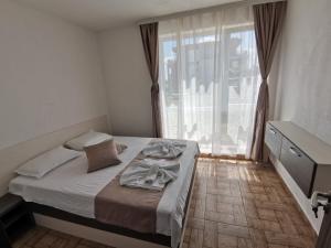 a bedroom with a bed and a large window at Arapya Apartments in Tsarevo
