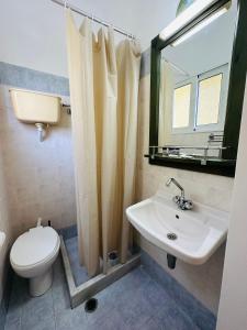 a bathroom with a sink and a toilet and a mirror at Ancora Hotel in Poros