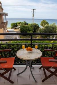 un tavolo su un balcone con 2 bicchieri di succo d'arancia di Vaso Alykanas Studios ad Alikanás