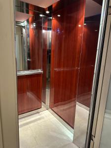 a walk in shower with wooden walls and a glass door at Ancora Hotel in Poros