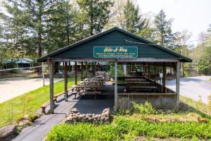 een paviljoen met tafels en banken in een park bij Hide-A-Way Waterfront Cottages in Lake Luzerne