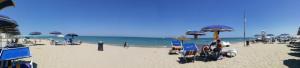a beach with umbrellas and people sitting on the sand at Alba Sweet in Alba Adriatica