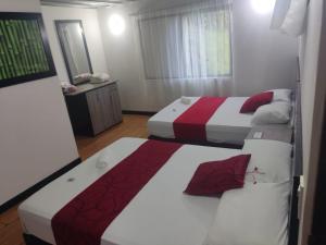 a bedroom with two beds and a mirror at FINCA HOTEL SANTO TOMAS REAL in Rionegro