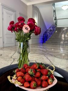 a plate of strawberries and a vase with flowers at RiverRun in Sukhum