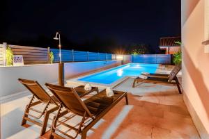 eine Terrasse mit 2 Stühlen und ein Pool in der Nacht in der Unterkunft Apartments Lara in Medulin