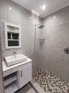 La salle de bains blanche est pourvue d'un lavabo et d'une douche. dans l'établissement 20 Montego Bay - Caribbean Estates, à Port Edward
