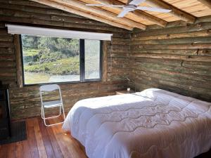 ein Schlafzimmer mit einem Bett, einem Fenster und einem Stuhl in der Unterkunft CABAÑA SIERRAS de CORDOBA in San Clemente