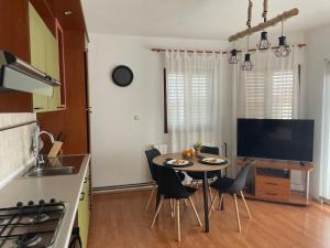 a kitchen with a table with chairs and a television at Apartman Morena in Vlašići