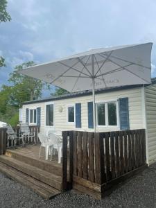 a mobile home with an umbrella on a wooden deck at Le clos de Banes in Banes