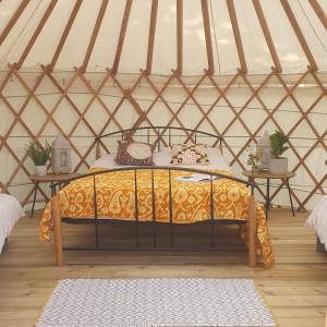 a bed in a yurt with two tables at The Lawn Yurt in Tullow