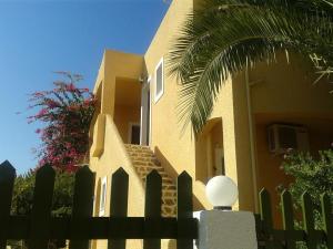 a yellow house with a fence and a palm tree at Eriketi Studios in Agia Marina Aegina