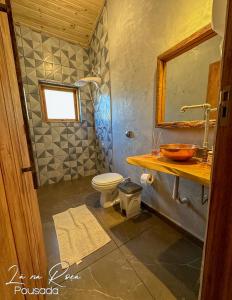La salle de bains est pourvue de toilettes, d'un lavabo et d'un miroir. dans l'établissement Pousada La na Roça, à Paraisópolis