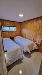 two beds in a room with wooden walls at RAMAL LODGE CONSTITUCION in Constitución