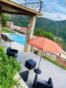 eine Terrasse mit einem Sonnenschirm und Stühlen sowie einem Pool in der Unterkunft Chão da Relva - Turismo & Natureza in Loriga